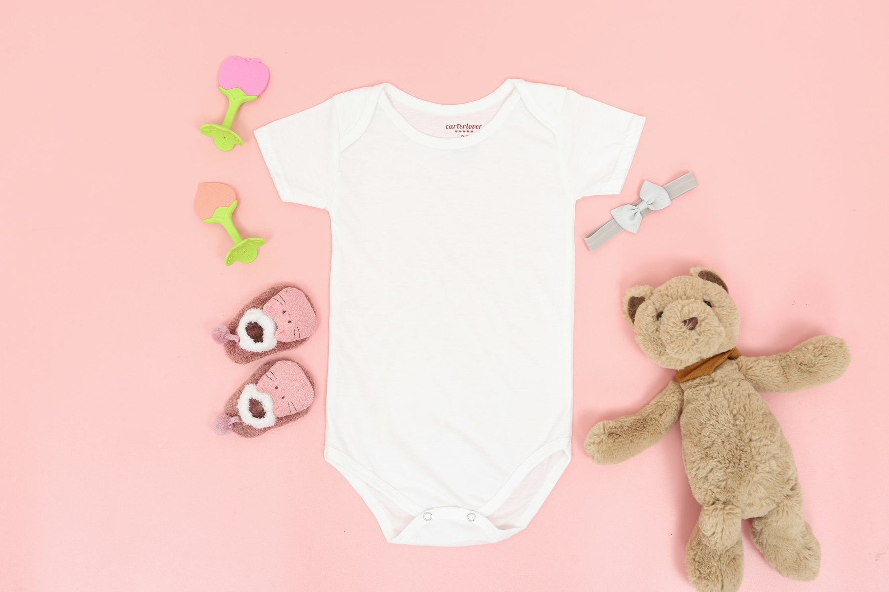 Mommy & Baby Yoga 3 (Unsplash) Baby onesie, teddy bear and booties on a pink background